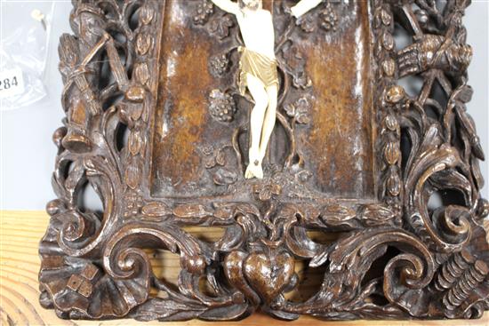 A 19th century European carved walnut and ivory crucifix, the ivory Corpus Christi on a pierced plaque decorated with angels, scrolls a